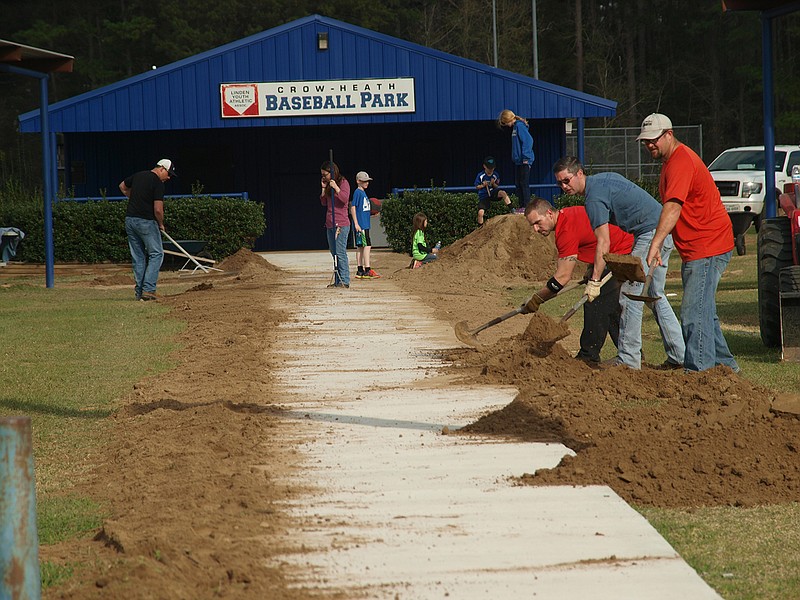 Lance Bynum, Marcus Smallwood and Curtis Lane, Kerry Wells, Amy Lane and others shovel dirt along the new sidewalks at Crow-Heath Baseball Park.
