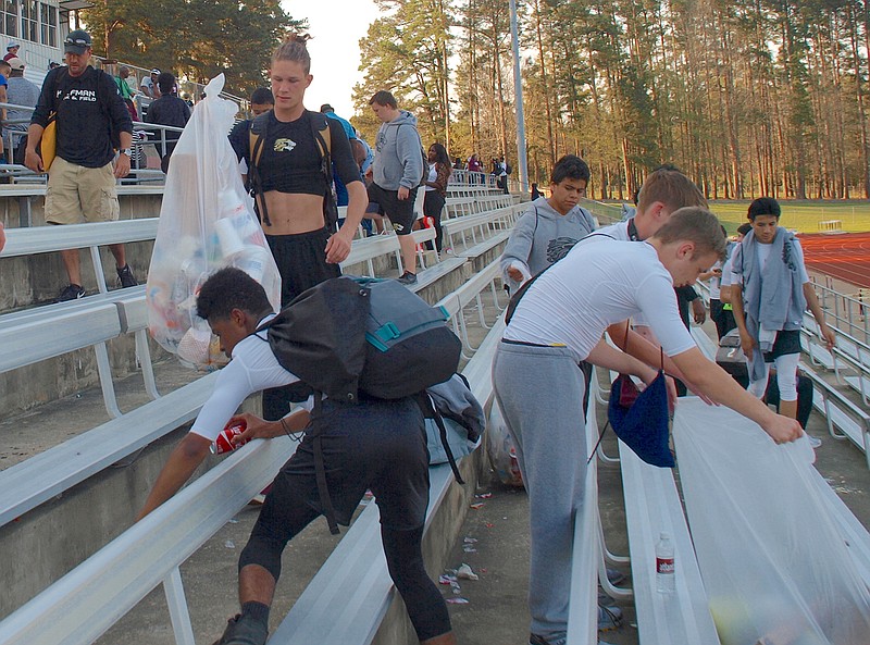 Members of the Kaufman, Texas, boys' team pick up trash at the end of the Runnin' Rabb Relays on Saturday in Atlanta, Texas. Leaving the hometown's stands clean after a track meet is a team-spirit and character builder for the Kaufman track program under the direction of Jeff Lester. 