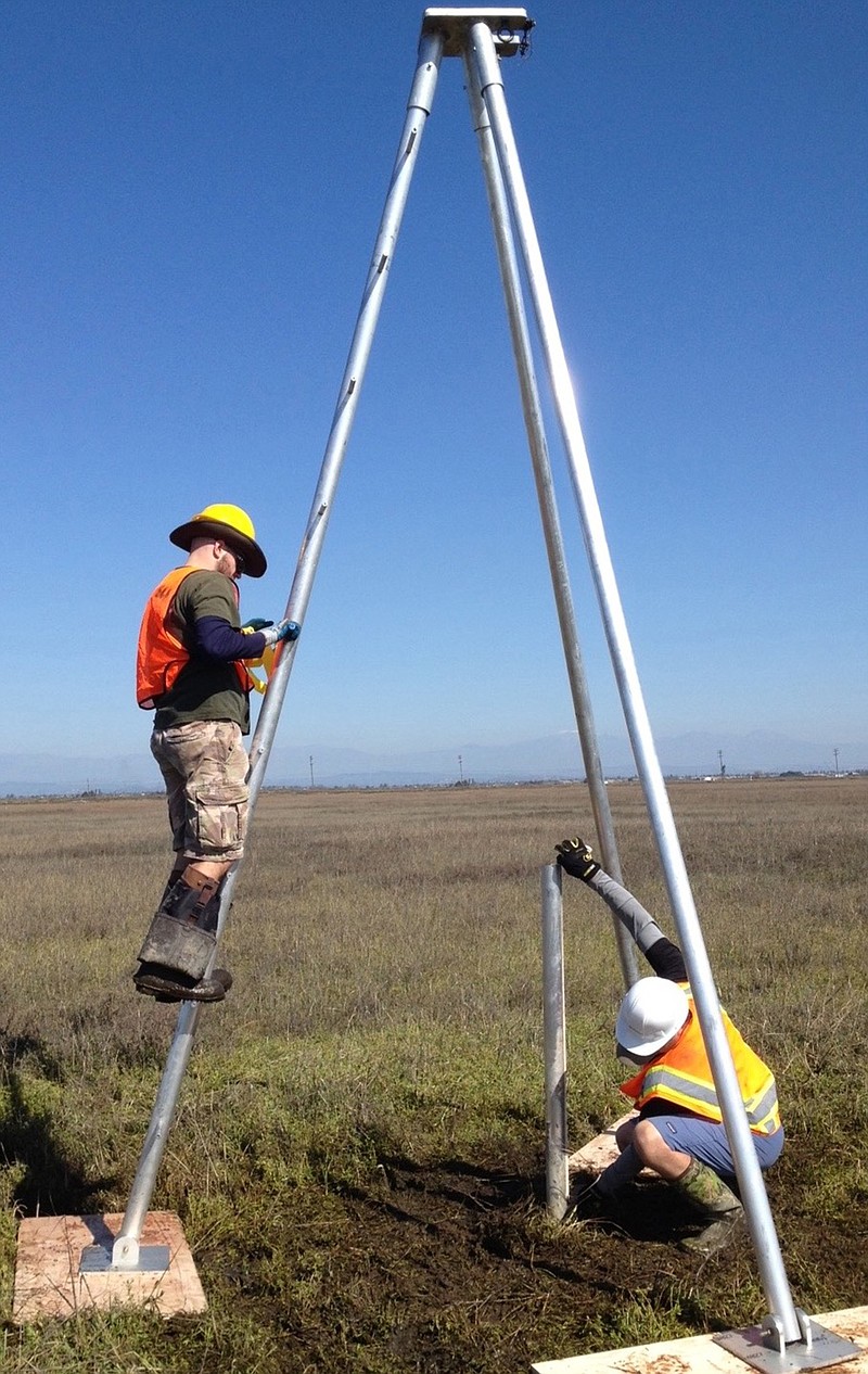 Researchers insert a pipe deep into sediment to extract a cross section to determine the seismic history of the Seal Beach area. 