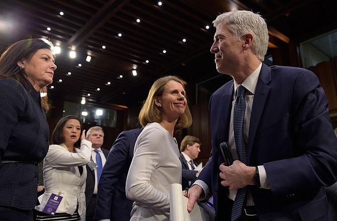 Supreme Court Justice nominee Neil Gorsuch, right, stands up during a break in his testimony on Capitol Hill in Washington, Wednesday, March 22, 2017, during his confirmation hearing before the Senate Judiciary Committee. Former Sen. Kelly Ayotte, R-N.H., left, and Gorsuch's wife Marie Louise Gorsuch, second from right, join him. 