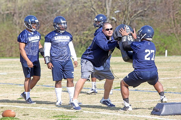 Lincoln defensive coordinator Phil Pitts leads players through a drill Wednesday as the Blue Tigers opened spring practice.