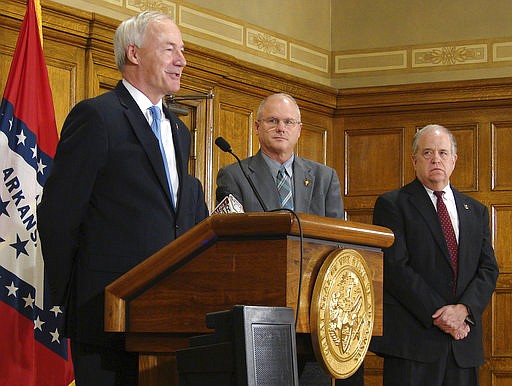 Gov. Asa Hutchinson, left, speaks to reporters Wednesday, March 22, 2017, at the state Capitol in Little Rock, Arkansas, after signing a bill allowing concealed handguns at colleges, bars and most government buildings if a permit-holder has completed eight hours of active-shooter training.