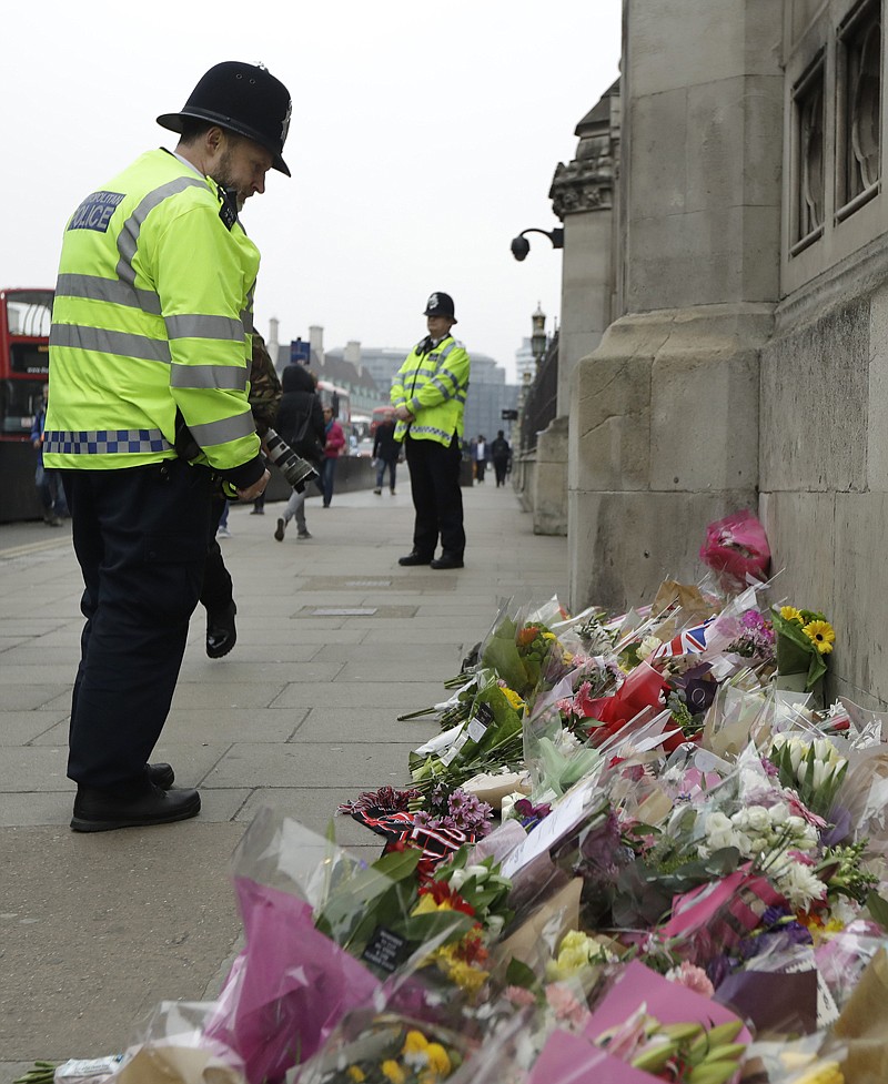 Police officers look Friday at floral tributes to victims of Wednesday's attack outside the Houses of Parliament in London.