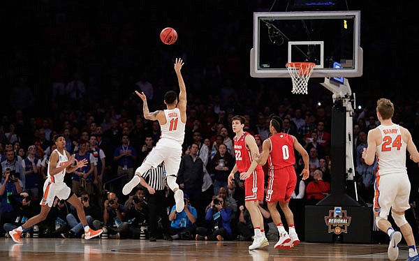 Florida guard Chris Chiozza (11) puts up a last-second 3-pointer for the game-winning points against Wisconsin in overtime of an East Regional semifinal game in New York. Florida won 84-83.