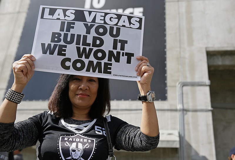Monette Bonilla, of San Jose, Calif., holds up a sign outside the Oakland Coliseum before the start of a rally to keep the Oakland Raiders from moving Saturday, March 25, 2017, in Oakland, Calif. NFL owners are expected to vote on the team's possible relocation to Las Vegas Monday or Tuesday at their meeting in Phoenix.