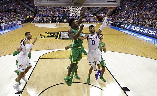 Kansas guard Frank Mason III (0) drives to the basket past Oregon forward Jordan Bell during the first half of a regional final of the NCAA men's college basketball tournament, Saturday, March 25, 2017, in Kansas City, Mo. 