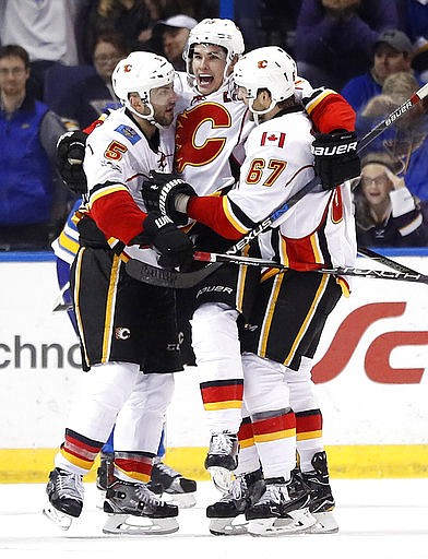 Calgary Flames' Sean Monahan, center, is congratulated by teammates Mark Giordano (5) and Michael Frolik, of the Czech Republic, after scoring the game-winning goal during overtime of an NHL hockey game against the St. Louis Blues Saturday, March 25, 2017, in St. Louis. The Flames won 3-2 in overtime.