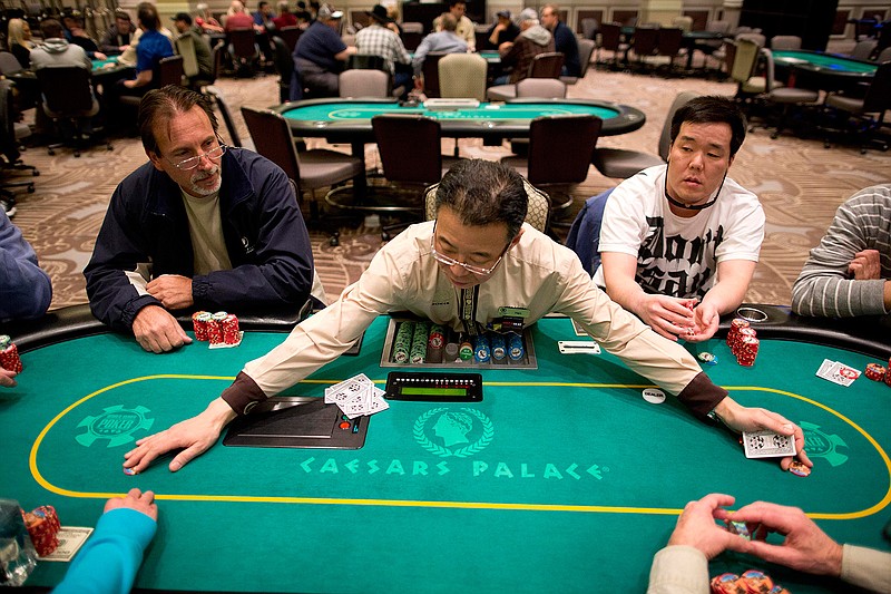 In this Feb. 27, 2013 file photo, dealer Han Kim, center, gathers up chips after a hand of Texas Hold 'em at a poker room in Caesar's Palace in Las Vegas.  Unlike the 2000s when casinos competed to lure fans of the game, poker's appeal has been weakening during this decade. Strip casinos had 405 tables and made $97 million in 2007. In contrast, the game only netted casinos $78 million last year after the number of tables decreased to 320. 