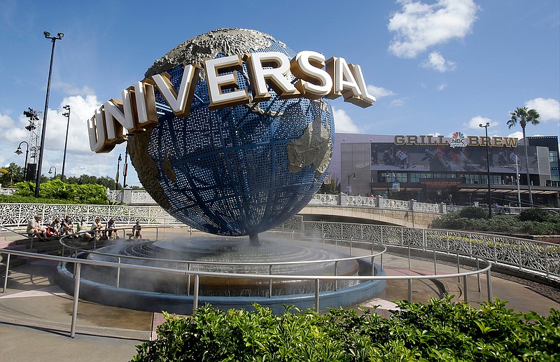 In this Thursday, Oct. 22, 2015 file photo, park guests relax and cool off with a water mist under the globe at Universal Studios City Walk in Orlando, Fla. Orlando's top tourist destinations, Walt Disney World, Universal Orlando, SeaWorld and several resorts are in legal battles about how much they're worth with the local property appraiser and tax collector.