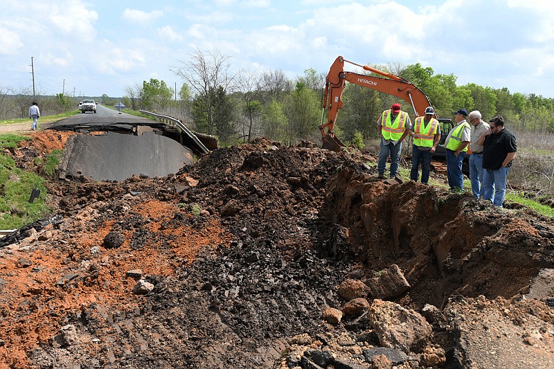 Members of Cleve Batte Construction Inc., Tyson Foods representatives and residents look at the hole left when a culvert collapsed Sunday on Miller County Road 64.