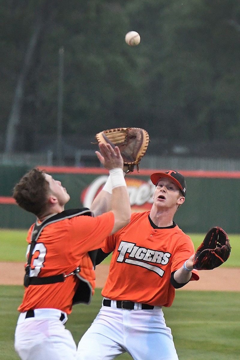 Texas High's Kyle Choate, left, calls for a tipped ball as pitcher Colby Adkins comes in for the catch Tuesday during the first inning against Greenville at Tiger Park in Texarkana, Texas.
