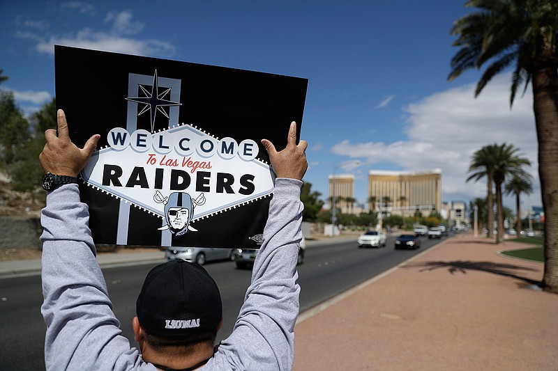 A man celebrates holding a Raiders sign, Monday, March 27, 2017, in Las Vegas. NFL team owners approved the move of the Raiders to Las Vegas in a vote at an NFL football annual meeting in Phoenix. 