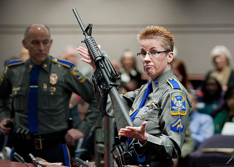 In this Jan. 28, 2013, file photo, firearms training unit Detective Barbara J. Mattson, of the Connecticut State Police, holds up a Bushmaster AR-15 rifle, the same make and model of gun used by Adam Lanza in the Sandy Hook School shooting, for a demonstration during a hearing of a legislative subcommittee reviewing gun laws, at the Legislative Office Building in Hartford, Conn. Gun control advocates are asking the Connecticut Supreme Court for permission to file briefs in an appeal involving the rifle used in the 2012 Newtown school shooting. They say a judge's 2016 decision to dismiss a wrongful-death lawsuit by Newtown victims' families against the rifle's maker sets a bad precedent.