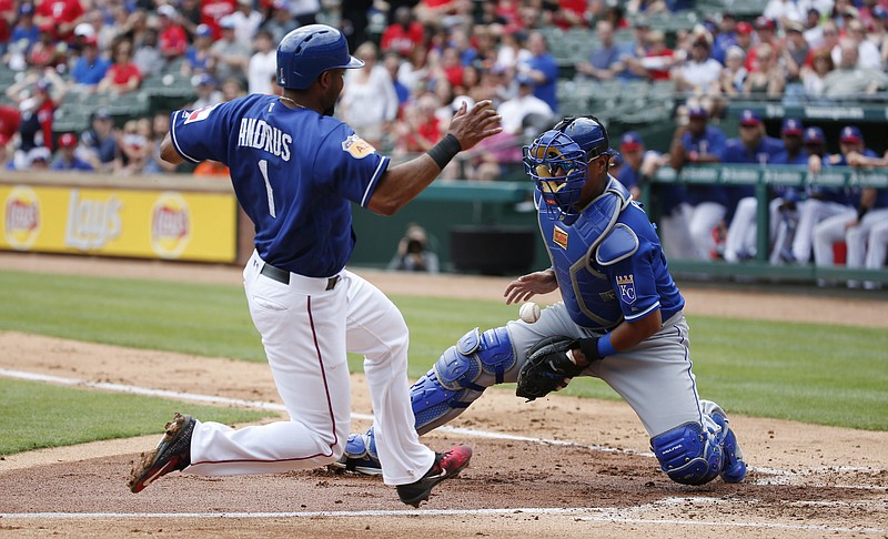 Texas Rangers' Elvis Andrus (1) scores a run as Kansas City Royals catcher Salvador Perez (13) fails to control the ball at home during the second inning of an exhibition baseball game Saturday, April 1, 2017, in Arlington, Texas. 