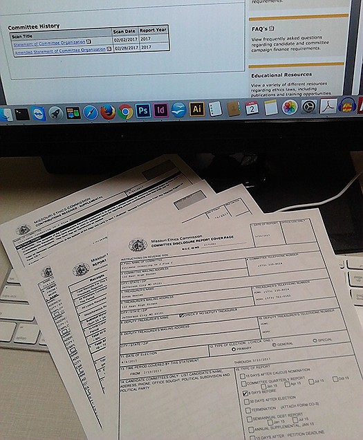 Copies of campaign committee disclosure reports printed from the Missouri Ethics Commission website sit on a computer keyboard. (News Tribune photo illustration)