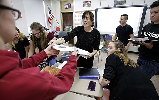 High school teacher Natalie O'Brien, center, hands out papers March 8 during a civics class called "We the People" at North Smithfield High School in Rhode Island. More states are requiring graduating high school students to know at least as much about the U.S. founding documents as immigrants passing a citizenship test. Boosting civics literacy has been a bipartisan cause. However, some advocates said a mandate to test government trivia is too simplistic.