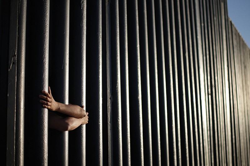 In this June 13, 2013, file photo, hands from Daniel Zambrano of Tijuana, Mexico, hold on to the bars that make up the border wall separating the U.S. and Mexico as the border meets the Pacific Ocean in San Diego. One potential bidder on President Donald Trump's border wall with Mexico wanted to know if the government would help if its workers came under "hostile attack." With bids due Tuesday, April 4, 2017, on the first design contracts, companies are preparing for the worst if they get the potentially lucrative but controversial job.