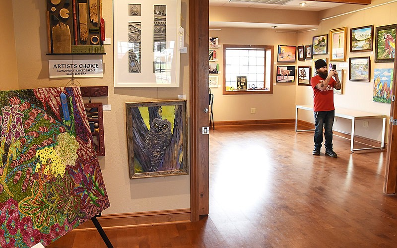 James Porello takes pictures of the art work hanging at Capital Arts Gallery on Missouri Boulevard in advance of the Art Around Town Gallery Crawl April 7, 2017.