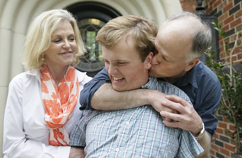 In this photo made Saturday, April 1, 2017, Clay Heighten, right, and Debra Caudy, left, embrace their autistic 19-year-old son Jon Heighten as they pose for a photo at their home in the Dallas area town of University Park, Texas. Jon Heighten's parents are helping lead a 29-acre housing development and community for autistic adults that will break ground in the coming months.