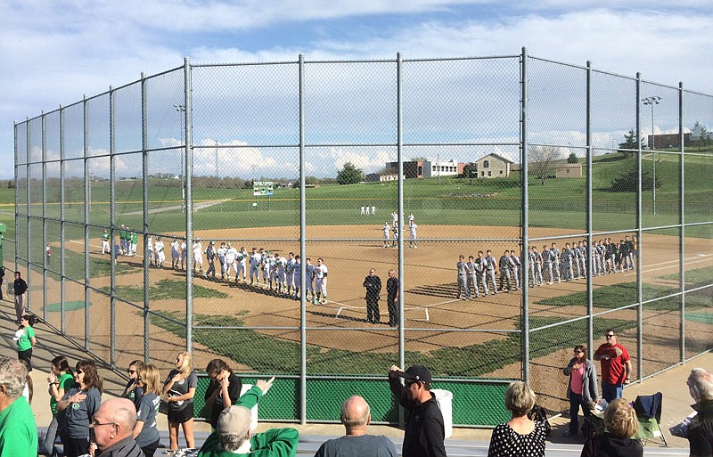 Spectators, players, coaches and officials stand for the National Anthem in advance of a baseball game between the Blair Oaks Falcons and Fulton Hornets on Monday, April 10, 2017 in Wardsville.