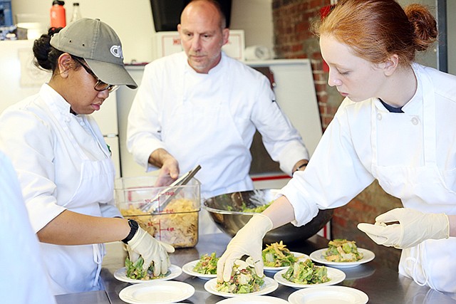 Rock Bridge High School students Alli Bond, right, 18, and Tyra Byas, 18, prepare upper class salads for guests Tuesday under the tutelage of Jeff Rayl during Dinner for a Difference at The Millbottom. Hosted by the Central Missouri Community Action to raise awareness on socio-economic inequality, guests were served food according to three groups of wealth: upper class, middle class and the impoverished. Rock Bridge High School and Battle High School students from the Columbia Area Career Center prepared the meal.