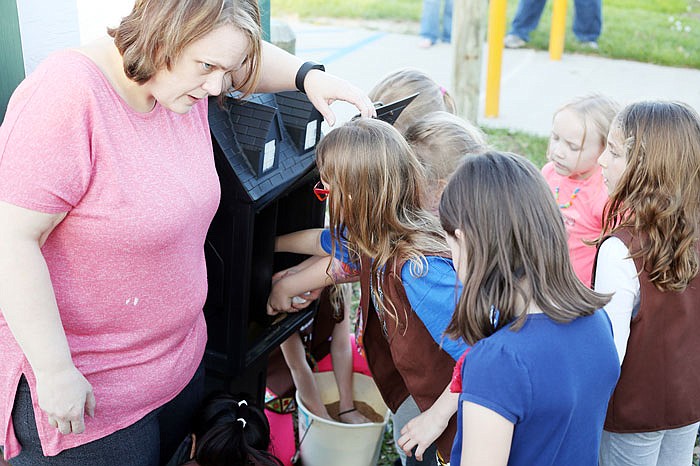 In this April 2017 photo, Girl Scout leader Lisa Cook, left, keeps an eye on Brownie Girl Scouts as they put sand in the bottom of a mini-library during a dedication held at the Cole County Jaycee Park. 