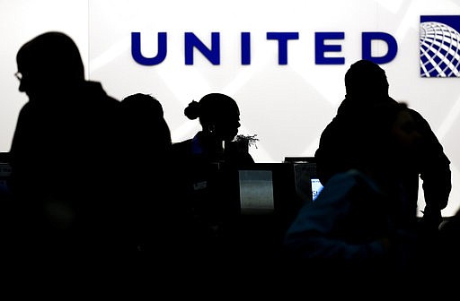 In this Saturday, Dec. 21, 2013, file photo, travelers check in at the United Airlines ticket counter at Terminal 1 in O'Hare International Airport in Chicago. 