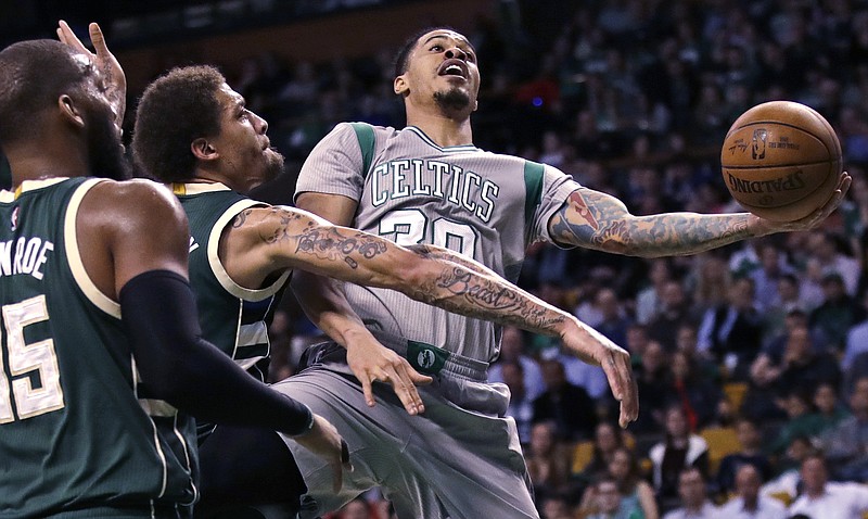 Boston Celtics forward Gerald Green (30) tosses up a shot as he is hit by Milwaukee Bucks forward Michael Beasley, center, on a drive to the basket during the first quarter of an NBA basketball game in Boston, Wednesday, April 12, 2017. 