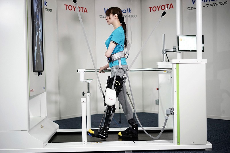 A model demonstrates the Welwalk WW-1000, a wearable robotic leg brace designed to help partially paralyzed people walk at the main system with treadmill and monitor, at Toyota Motor Corp.'s head office in Tokyo, Wednesday, April 12, 2017. Toyota Motor Corp.'s Welwalk WW-1000 system is made up of a motorized mechanical frame that fits on a person's leg from the knee down.