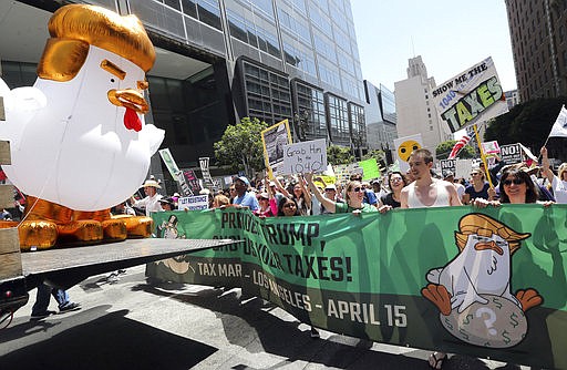 A giant inflatable "Chicken Don" leads demonstrators protesting President Donald Trump's failure to release his tax returns and a host of other issues during a march and rally in downtown Los Angeles Saturday, April 15, 2017.