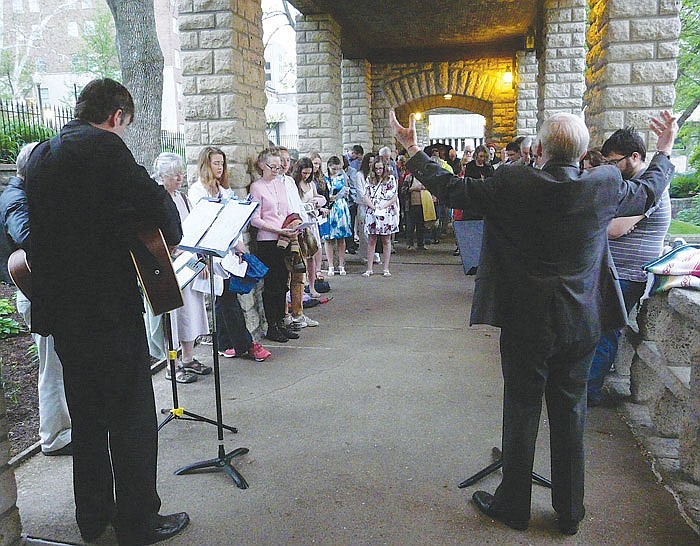Several dozen people attended Sunday's annual Easter sunrise service, held at the Governor's Gardens by First Presbyterian Church.  After a light rain grew more steady, the Rev. Dave Henry, right foreground, moved the service to under the nearby covered walkway.