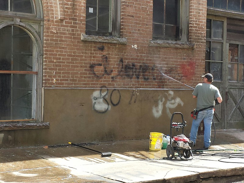 Graffiti is power washed from the 1894 City Market in Downtown Texarkana on Monday afternoon. The building, formerly known, as the Ritchie Grocery Building, was defaced over the weekend. The owner is taking to social media to investigate. 