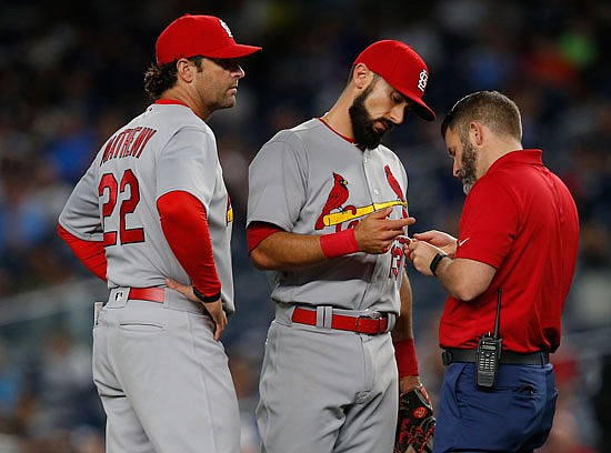 Cardinals first baseman Matt Carpenter has his finger taped by trainer Adam Olsen as manager Mike Matheny looks on during the first inning of Sunday night's game against the Yankees in New York.