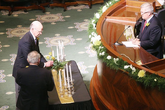 Sen. Ed Emery, R-Lamar, top left, places a rose in a vase during a memorial ceremony Tuesday at the Capitol remembering former lawmakers who have died in recent years.
