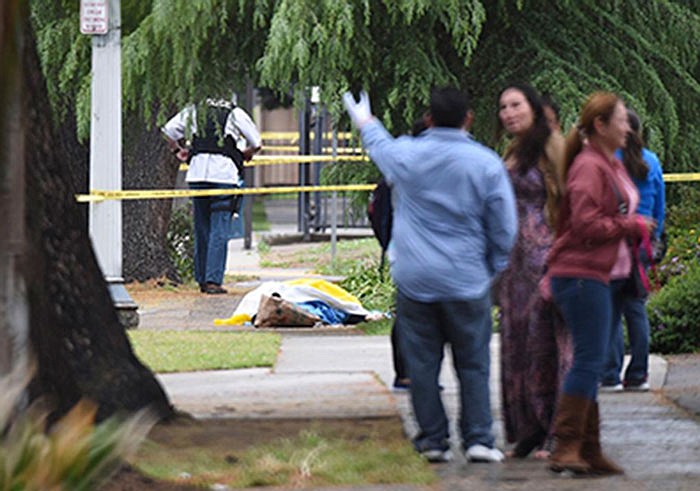 Evacuated office workers stand by, with a deceased shooting victim down on the sidewalk Tuesday in Fresno, California.