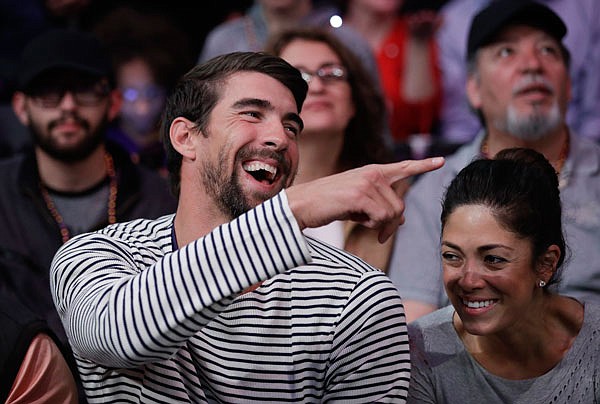 In this March 21 file photo, Michael Phelps and his wife, Nicole Johnson, smile during an NBA game between the Lakers and the Clippers in Los Angeles.