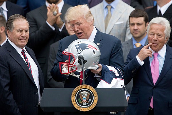 President Donald Trump, flanked by Patriots head coach Bill Belichick and owner Robert Kraft, holds a Patriots football helmet and jersey during a ceremony Wednesday on the South Lawn of the White House in Washington, where he honored the NFL champions for their Super Bowl LI victory.