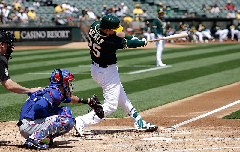 Oakland Athletics' Ryon Healy (25) hits an RBI-single in front of Texas Rangers catcher Robinson Chirinos during the first inning of a baseball game in Oakland, Calif., Wednesday, April 19, 2017.