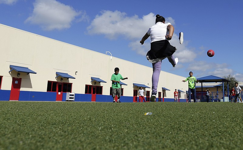 In this Sept. 10, 2014, file photo, children play kickball at the Karnes County Residential Center, a temporary home for immigrant women and children detained at the border, in Karnes City, Texas. 