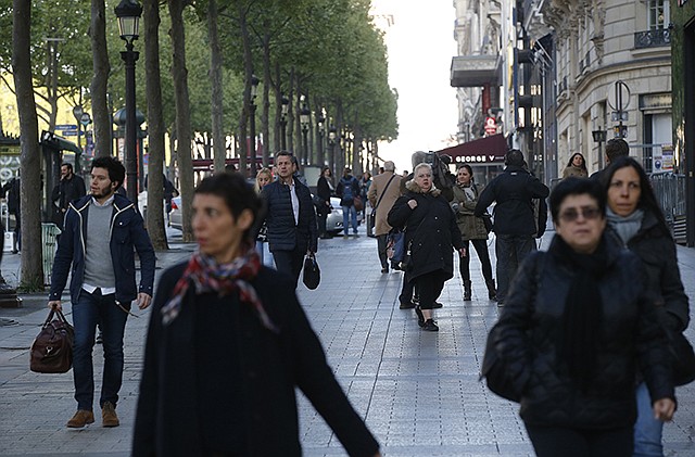 People walk on the Champs-Elysees boulevard Friday in Paris. Paris' iconic boulevard is reopen and picking up its usual early morning routine Friday after a gunman opened fire on police, killing one officer and wounding three people before police shot and killed him.