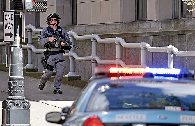 A police officer carrying a rifle runs past a downtown building and near the scene of a shooting Thursday involving several police officers in downtown Seattle.