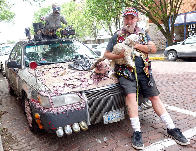 John McMahon and his friend's dog, Ted, lean on the hood of his zombified car. McMahon stopped in Fulton this week on his way home to Canada from the Houston Art Car Parade.