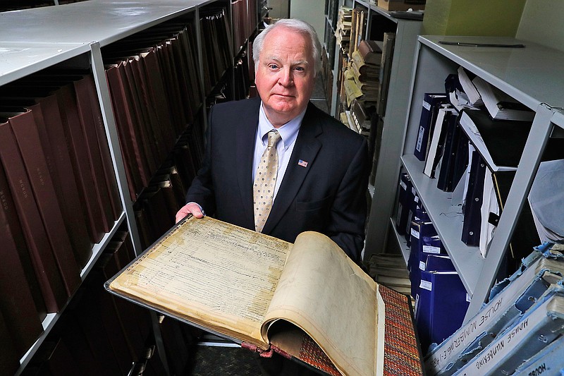 Bernard Youngblood, Wayne County Register of Deeds, poses with an old deed registry book in Detroit, Wednesday, April 19, 2017. Youngblood recounted a case in his office, when a man came to file a quitclaim deed transferring ownership on a property. A clerk recognized the address and went to a co-worker with a question. "Are you selling your house to that guy?" she asked. She wasn't. Youngblood said he faked a computer outage, leaving the would-be fraudster waiting at the counter. It bought enough time to get deputies to respond and make an arrest. 