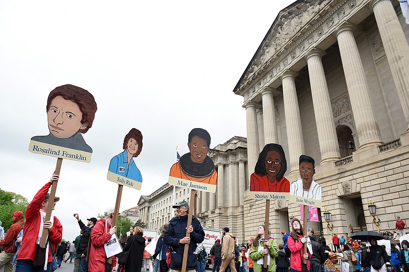 People hold signs of pioneering women in science in front the U.S. Environmental Protection Agency during the March for Science in Washington, Saturday, April 22, 2017. Scientists, students and research advocates rallied from the Brandenburg Gate to the Washington Monument on Earth Day, conveying a global message of scientific freedom without political interference and spending necessary to make future breakthroughs possible. 