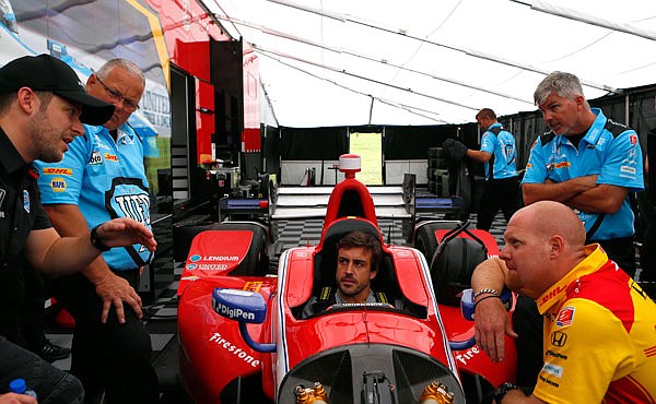 Formula 1 driver Fernando Alonso (center) talks with crew members as he is fitted for an IndyCar before Sunday's Indy Grand Prix of Alabama in Birmingham, Ala. (AP Photo/Butch Dill)