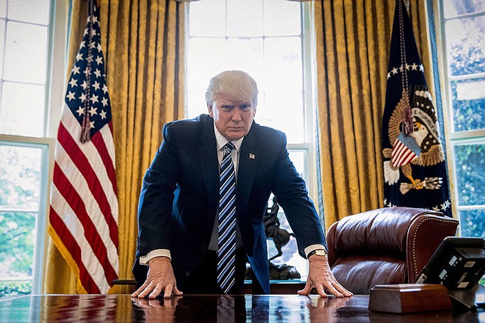 President Donald Trump poses for a portrait in the Oval Office in Washington.