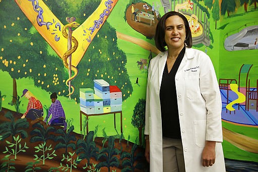 In this photo taken Friday, April 7, 2017, Dr. Kirsten Bibbins-Domingo poses by a mural in the lobby of her office in San Francisco. Draft recommendations from the US Preventive Services Task Force ditch the old advice against PSA screening and say whether to get tested should be left up to men aged 55 to 69 after being informed of the potential benefits and harms. The advice would bring the influential panel more in line with other major doctor groups.