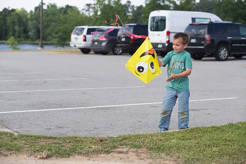 Eli Dugan, 5, picks up a kite that plummeted to the ground moments before Tuesday at Bringle Lake Park. "It's like a bird that lost a wing, but then it grows back," Dugan said to explain the kite's problems staying in the air. 
