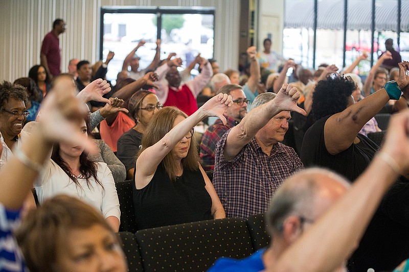 Attendees of the "Missing Person's Town Hall" held by Bowie and Miller County Democrats show their disapproval Tuesday of a video statement made by U.S. Rep. John Ratcliffe at Twin City Event and Conference Center. The event was a panel discussion of local politicians and health care experts about the Affordable Care Act and its future. 