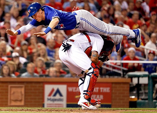 Chris Coghlan of the Blue Jays leaps above Cardinals catcher Yadier Molina to score during the seventh inning of Tuesday night's game at Busch Stadium.